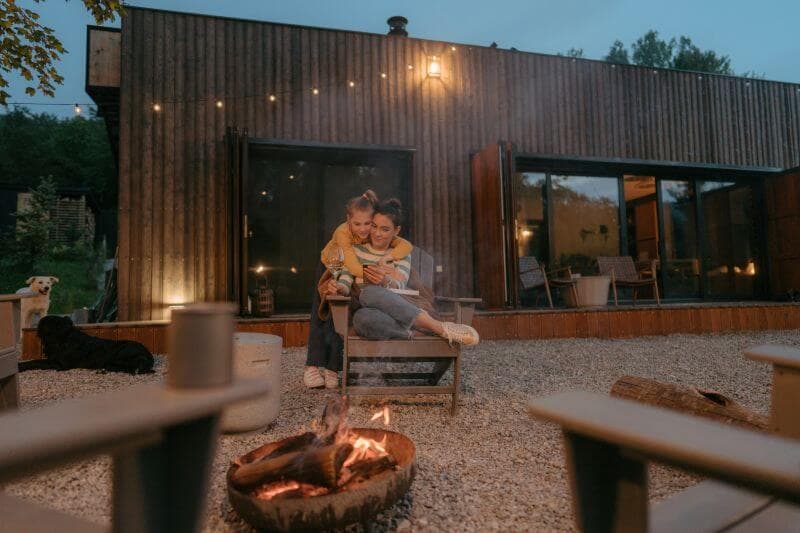 Mother and daughter cuddled by a backyard fire pit at dusk, enjoying their home's outdoor space — the kind of equity-building investment a HELOC can help fund