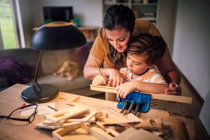 Mother and son working on a woodworking project together at home, focused and on task — like building a solid debt consolidation plan that sticks