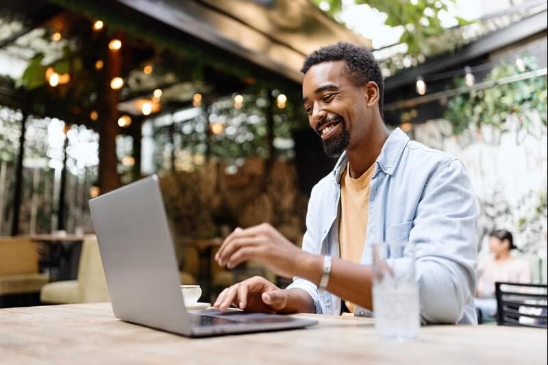 Man sitting at a table typing on a laptop.