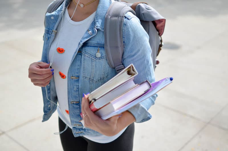 woman holding books wondering how long does it take to pay off student loans